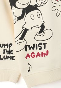 Cartón de Mickey Mouse en blanco y negro con el texto "TWIST AGAIN" y una nota musical sobre tela color crema.