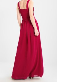 Fuchsia maxikjol med smockad bodice, breda axelremmar och flödande kjol. Tillverkad av lättviktig tyg med en slät textur.