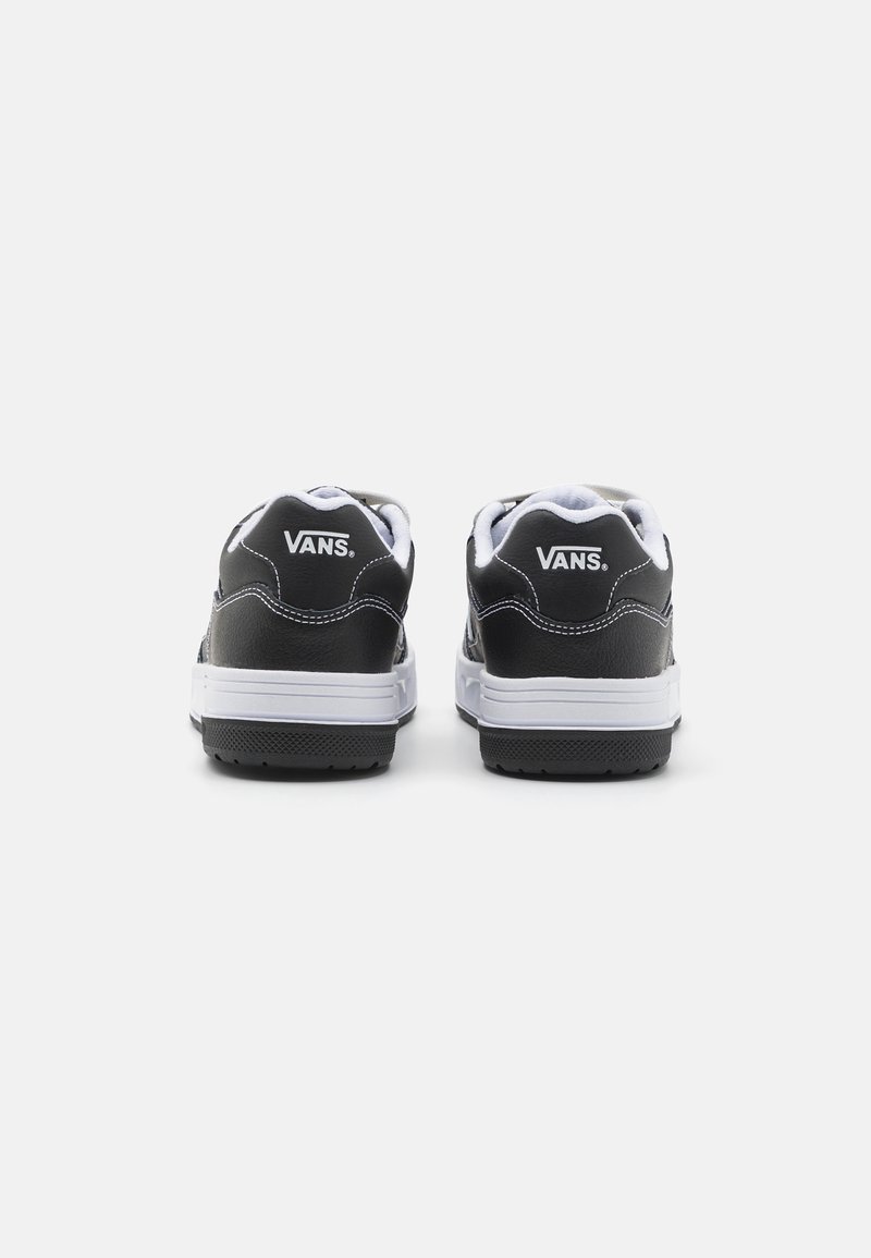 Baskets Vans en cuir noir présentant une semelle et des lacets blancs, avec une marque blanche sur les talons et des détails de coutures contrastants.
