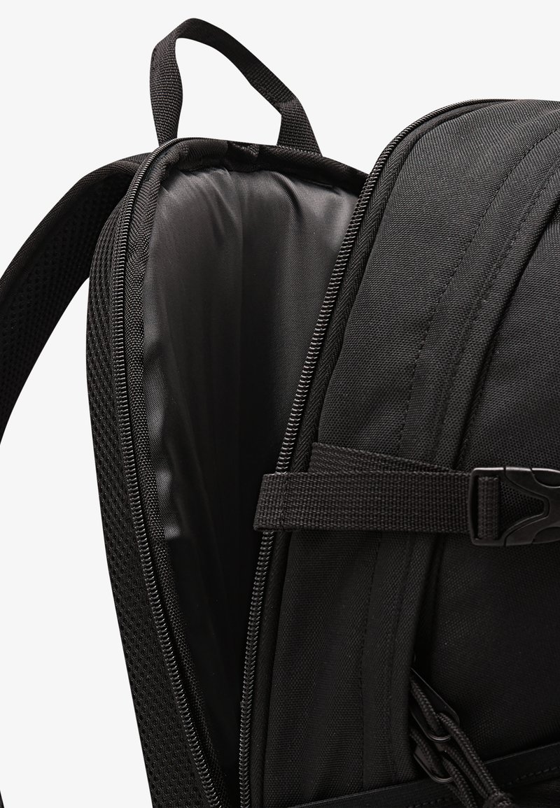 Sort rygsæk med polstret indvendigt rum, udstyret med en glat lynlås, justerbar strop og webbingdetaljer for øget funktionalitet.