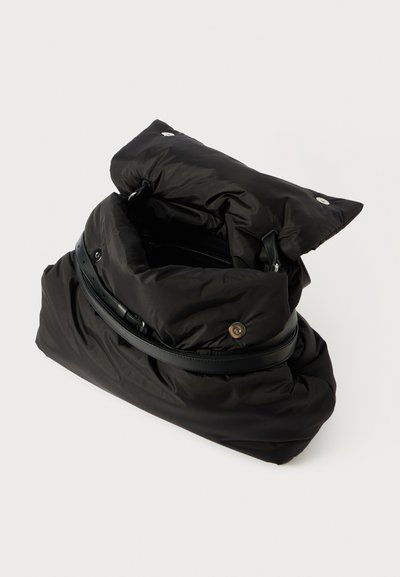 Μαύρη φουσκωτή τσάντα με σχέδιο διπλώματος, διαθέτει λείο δερμάτινο λουρί και μεταλλικά κουμπιά με κούμπωμα. Μαλακή, καπιτονέ υφή. Ορατό εσωτερικό.