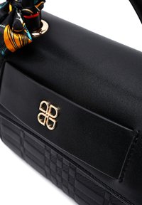 Borsa a spalla in pelle nera con rifiniture in metallo dorato. Presenta un fondo testurizzato con un motivo a rombi e un nastro decorativo con motivo sul manico.
