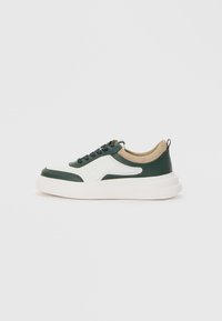 Green and white sneaker with a textured design, round toe, lace-up front, beige accents, and a thick white sole. Features a pull tab at the back.