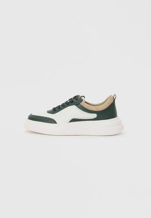 Green and white sneaker with a textured design, round toe, lace-up front, beige accents, and a thick white sole. Features a pull tab at the back.
