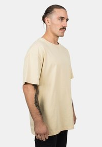 Beige cotton T-shirt with a relaxed fit, crew neck, and short sleeves. Features a smooth texture and minimalistic design.