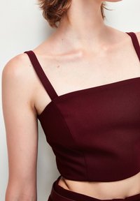 Bordeaux crop top med tunna band, strukturerad livstycke och jämn textur. Har en fyrkantig halsringning och en åtsittande design.