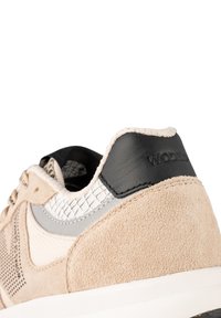 Baskets beiges en matériaux en daim et en cuir. Présentent un panneau texturé en argent, un accent de talon noir et des détails perforés sur le côté.