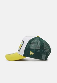 Gorra de camionero con una parte delantera blanca, visera amarilla y parte trasera de malla verde. Presenta un parche rectangular en la parte delantera con texto y detalles del logo.