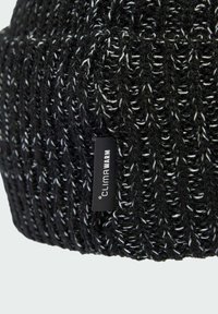 Stickad mössa i svart med vita prickar, med ett texturerat mönster. Inkluderar en liten svart etikett med "ClimaWarm"-logotyp.