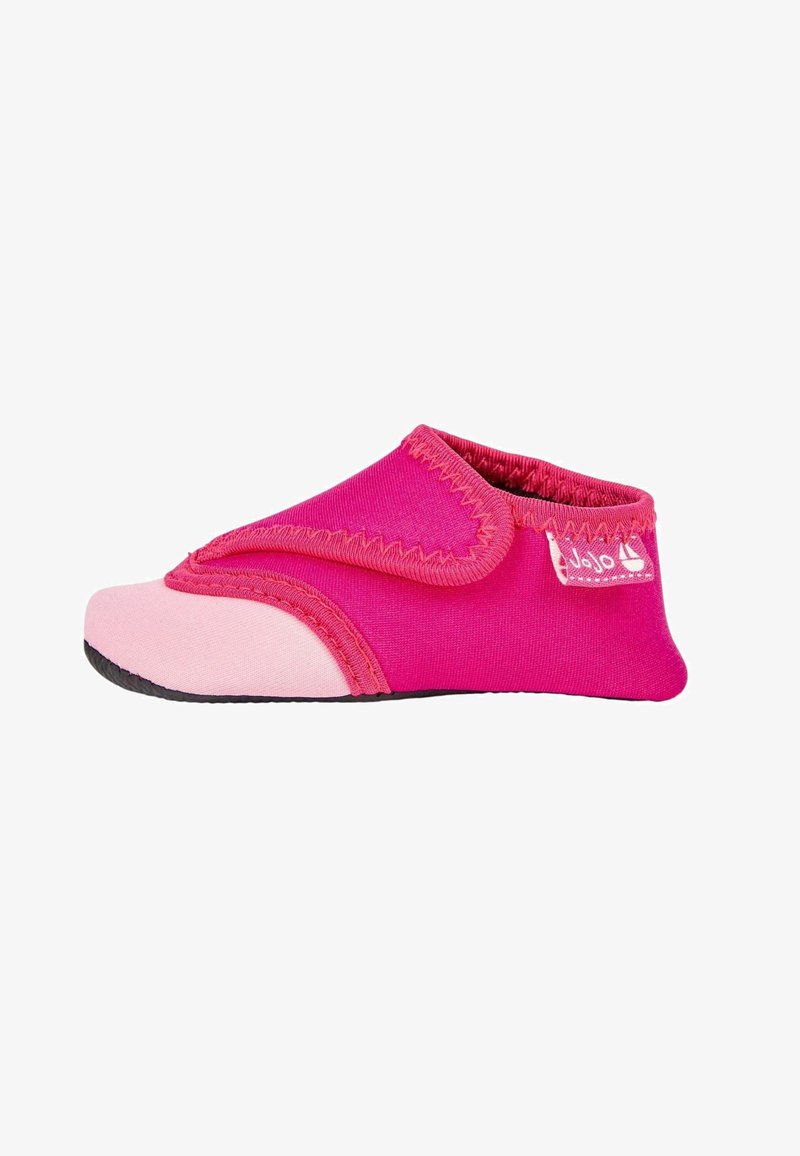 Chaussure en tissu rose avec une semelle en caoutchouc rose, dotée d'une sangle Velcro et de coutures contrastées le long des bords. Design léger et flexible.