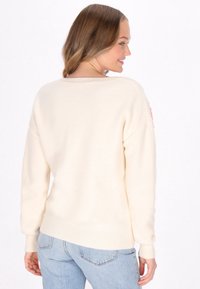 Crème-kleurige trui met een relaxed fit, ribbelboorden en -zoom, en een gestructureerde brei. Heeft een roze accent op de linker mouw.