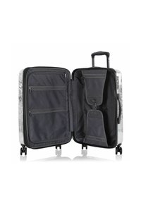 Harte Koffer mit glänzender schwarz-weißer Außenseite, ausgestattet mit einem geräumigen, organisierten Innenraum mit Netzfächern und einem ausziehbaren Griff.