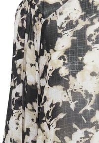 Blusa fluida con un motivo astratto in nero e beige, tessuto leggero, superficie testurizzata e dettagli con maniche arricciate.