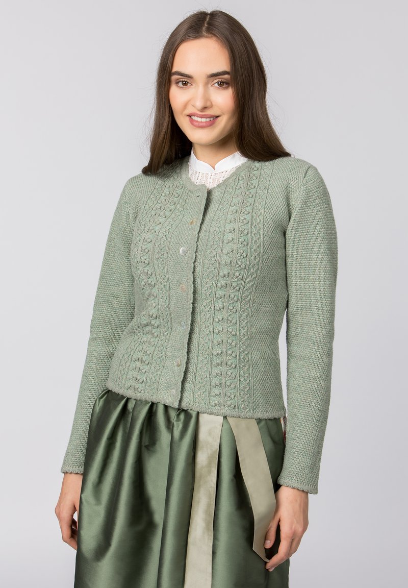 Helles grün gestricktes Cardigan mit einem strukturierten Muster, rundem Halsausschnitt und vorderen Knöpfen. Kombiniert mit einem dunkelgrünen Satinrock.