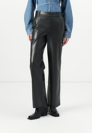 Zwarte nepleren broeken met een rechte snit, hoge taille en minimale stikseldetails. Gestyled met een blauwe denim top en zwarte haklaarzen.