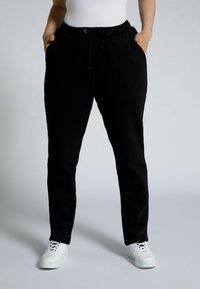 Zwarte sweatpants van zachte stof, met een elastische tailleband met trekkoord, zijzakken en een taps toelopend ontwerp.