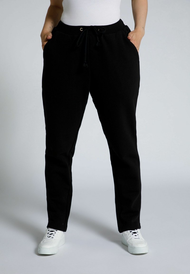 Zwarte sweatpants van zachte stof, met een elastische tailleband met trekkoord, zijzakken en een taps toelopend ontwerp.