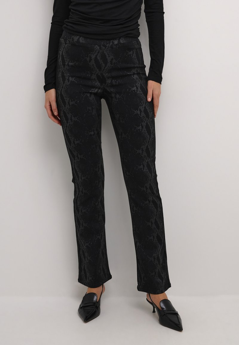 Zwarte slangenprint broek met een getailleerd silhouet, textuurstof en een lichte flared onderkant, gecombineerd metpuntige zwarte hakken.