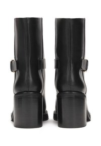 Botas de tobillo de cuero negro con un tacón cilíndrico y un pequeño detalle de correa. Textura suave con un diseño elegante y minimalista.