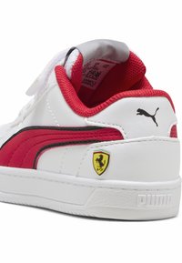 Zapatilla blanca con acentos rojos, rayas negras y el logo de Ferrari. Hecha de cuero y malla, cuenta con un collar acolchado y una suela texturizada.