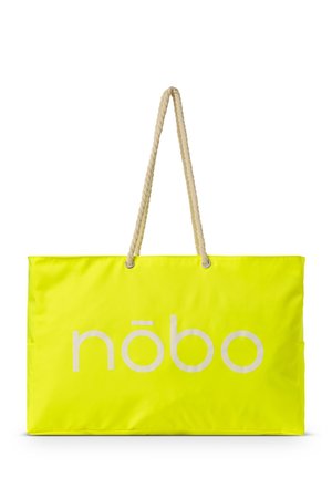 Sac fourre-tout jaune néon avec une surface lisse et brillante, présentant un grand logo blanc et deux poignées en corde tressée fixées avec du matériel en argent.