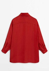 Blouse rouge texturée avec un col, des manches longues à poignets boutonnés, et une coupe décontractée, vue de dos.