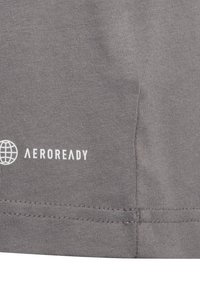 Grijze sportshirt van stof met een gladde textuur. Bevat het "AEROREADY" logo in het wit, gelegen aan de onderste linkerzijde.