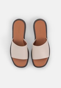 Light beige slide sandals with wide strap, brown insole, and black rubber outsole. Smooth texture; modern, minimalist design.