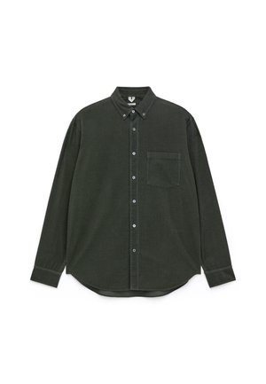 Dunkelgrünes Cordhemd mit Knopfleiste, langen Ärmeln, einer Tasche auf der linken Brust und einem abgerundeten Saum. Mit kontrastierenden Knöpfen.