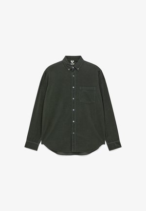 Dunkelgrünes Cordhemd mit Knopfleiste, langen Ärmeln, einer Tasche auf der linken Brust und einem abgerundeten Saum. Mit kontrastierenden Knöpfen.