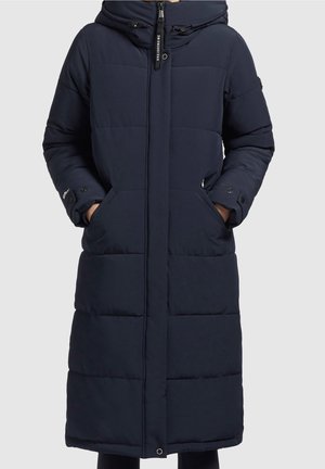 Mørkeblå polstret lang vinterjakke med hætte, lynlås foran, trykknapper, sidelommer og justerbare manchetremme. Hænder i lommerne.