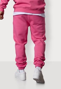 Rosa Jogginghose aus Baumwollmischung, mit elastischen Bündchen an den Knöcheln und einem lässigen Schnitt. Kombiniert mit weißen Sneakers.