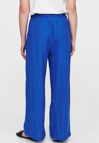 Blaue weite Hose mit elastischem Bund, glatter Textur und lässiger Passform, ohne sichtbare Muster oder Hardwaredetails.