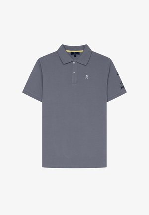 Polo gris de manga corta con dos botones, pequeño logo de palos de hockey cruzados en el pecho y detalle de texto en la manga derecha.