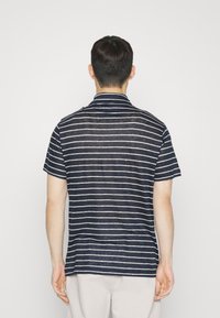 Camisa de manga corta navy con rayas horizontales blancas, diseño de cuello, tejido ligero y terminados limpios sin logotipos visibles.