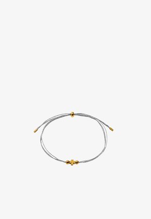 Regulowana srebrna pleciona bransoletka z akcentami złotych koralików i małym złotym zawieszka w kształcie koniczyny na środku.