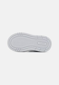Semelle de sneaker Puma en caoutchouc blanc, avec un motif de bande de roulement en zigzag, une texture lisse et un logo discret près du talon.