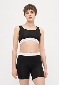 Fekete sportmelltartó és testhez simuló rövidnadrág, fehér "COPENHAGEN STUDIOS" logóval a derékpánton. Simább, elasztikus anyag, alapdesign, ujjatlan felső.