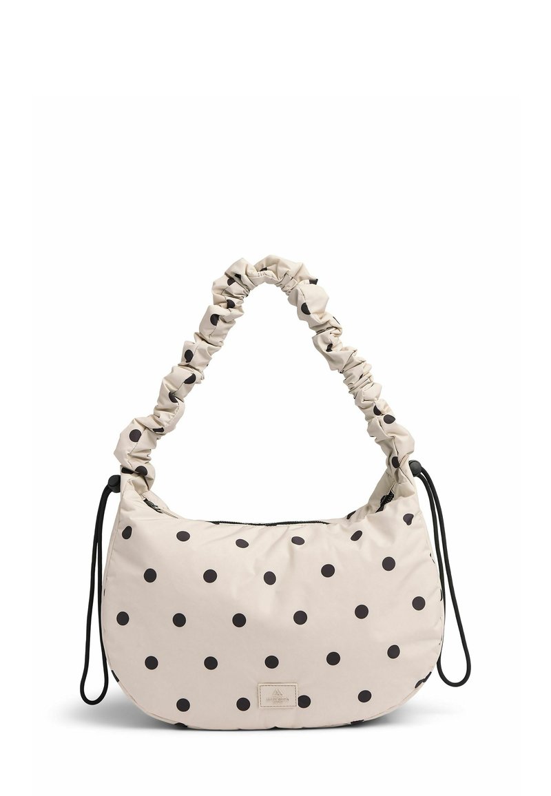 Beige stoftas med rund form, sorte prikker, en samlet strop og lynlåslukning; har et lille logo-plakette.