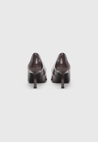 Καφέ δερμάτινα ψηλοτάκουνα παπούτσια με ομαλή επιφάνεια, που διαθέτουν μυτερή μύτη και κάθετη ραφή στο πλάι.