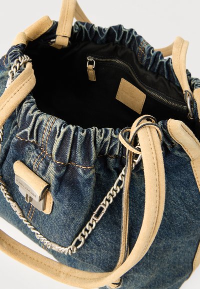 Τσάντα bucket από τζιν με κορδόνι, διακοσμητική τρέσα από καφέ σουέντ, ασημένια αλυσίδα, εσωτερική τσέπη με φερμουάρ και μεταλλική πλακέτα με το λογότυπο "Marc Jacobs".