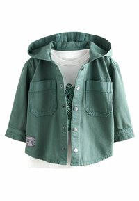 Jachetă denim verde cu glugă, nasturi metalici argintii, două buzunare la piept și un tricou alb dedesubt cu imprimeu grafic.
