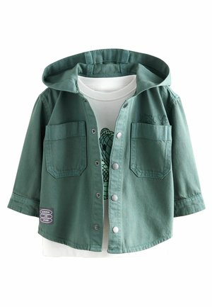 Giacca di jeans verde con cappuccio, chiusura a bottoni, due tasche sul petto e un patch "MAKE IT FUN"; indossata sopra una t-shirt bianca con grafica.