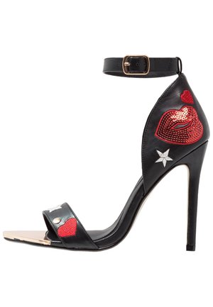 Sandalo nero con tacco alto e cinturino alla caviglia, decorato con labbra rosse in paillettes, cuori rossi e ricami di stelle bianche.