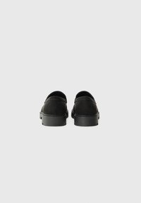 Schwarze Wildlederschuhe mit runder Form und niedrigem Profil. Verfügt über ein strukturiertes Obermaterial, eine robuste Gummisohle und minimale Details.