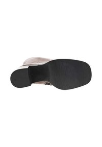 Semelle extérieure en caoutchouc noir d'une chaussure, lisse avec une surface texturée. Partie supérieure de couleur claire et douce partiellement visible.