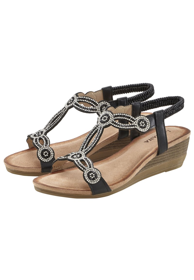 Schwarze Keilsandalen mit einem verzierten T-Riemen-Design, das silberne Akzente und ein strukturiertes Fußbett aufweist. Weiche Fütterung und elastische Knöchelriemen.