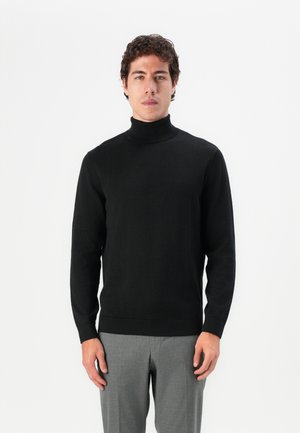 Maglione nero a collo alto realizzato in un morbido tessuto lavorato a maglia, con un design aderente e maniche lunghe, abbinato a pantaloni grigi.