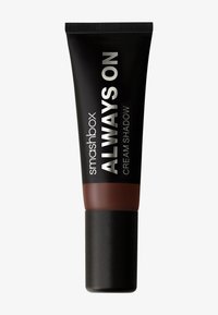 Ombre crème Smashbox Always On dans un tube noir avec du texte argenté. Le fond a une finition noir mat et une section de couleur marron.