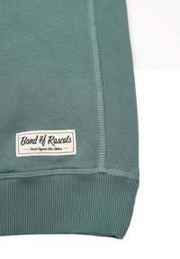 Grøn bomulds-sweatshirt med ribbet tekstur, elastisk kant og et syet mærke, der læser "Band of Rascals", som indikerer økologisk børnetøj.